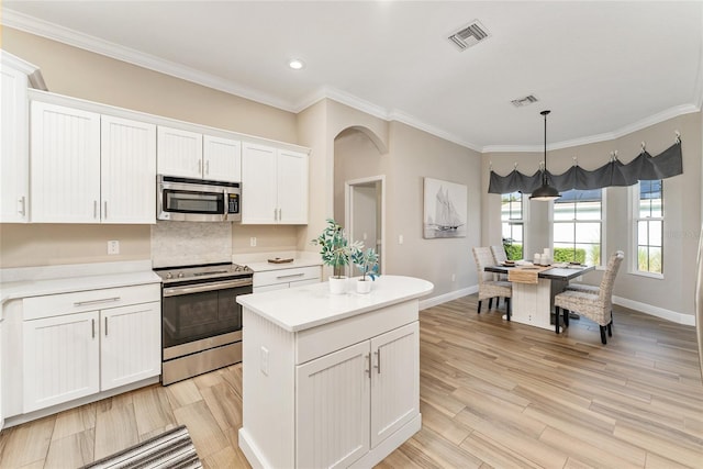 kitchen featuring hanging light fixtures, stainless steel appliances, light hardwood / wood-style flooring, and white cabinetry