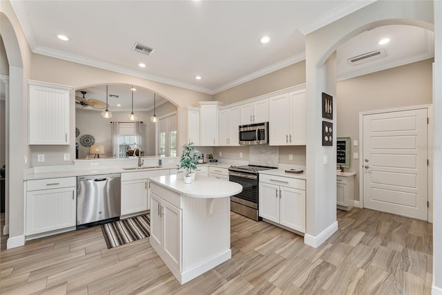 kitchen featuring appliances with stainless steel finishes, light hardwood / wood-style flooring, decorative light fixtures, and white cabinets