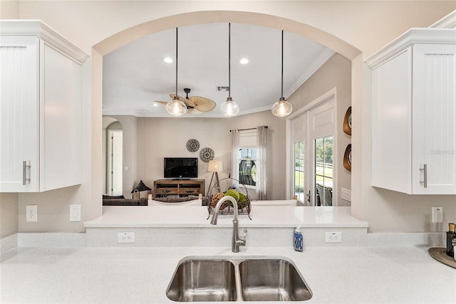 kitchen with ceiling fan, crown molding, white cabinetry, and sink