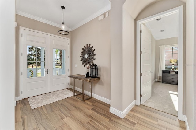 entryway featuring light wood-type flooring, ornamental molding, and plenty of natural light