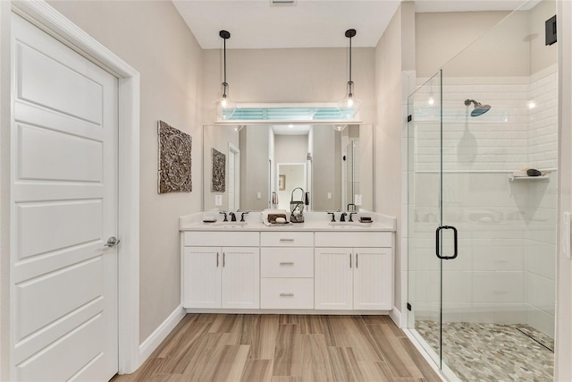 bathroom with hardwood / wood-style floors, a shower with door, and vanity