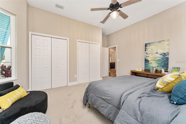 carpeted bedroom featuring two closets and ceiling fan