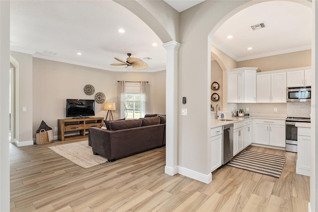 kitchen with appliances with stainless steel finishes, ceiling fan, white cabinets, and light hardwood / wood-style floors