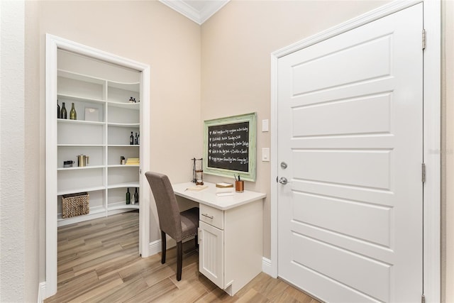 office space featuring light wood-type flooring, built in desk, and ornamental molding