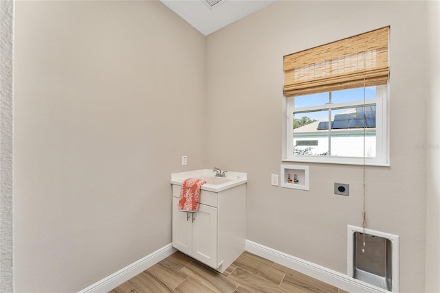 washroom with hookup for a washing machine, cabinets, light hardwood / wood-style floors, and electric dryer hookup