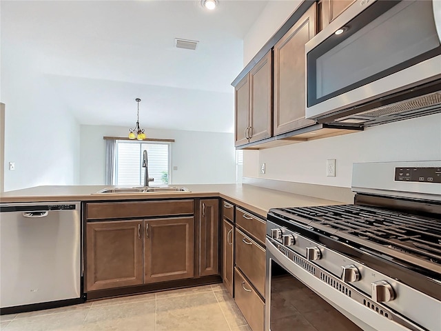 kitchen with decorative light fixtures, light tile patterned floors, appliances with stainless steel finishes, kitchen peninsula, and sink