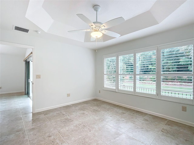 spare room featuring a raised ceiling, light tile patterned floors, and ceiling fan