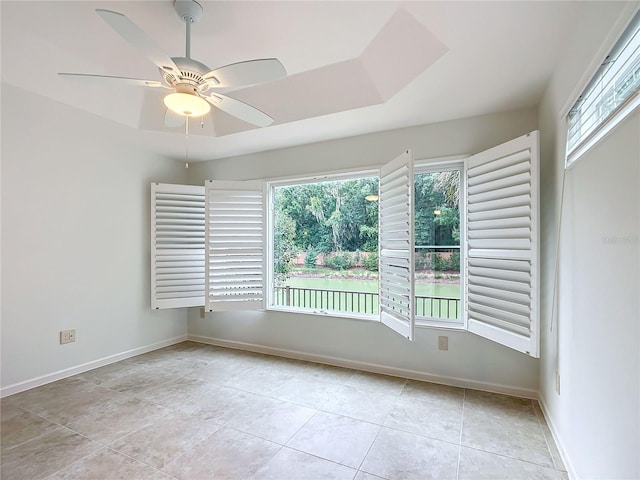 empty room featuring a wealth of natural light, ceiling fan, and light tile patterned floors