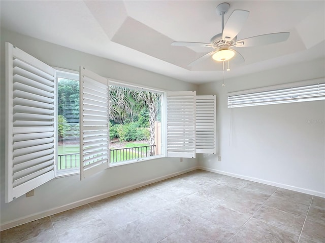 spare room featuring ceiling fan and a raised ceiling