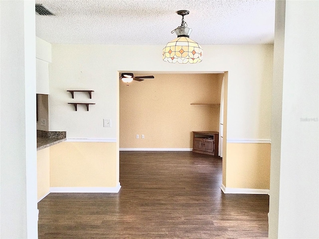 interior space featuring a textured ceiling, ceiling fan, decorative light fixtures, and dark hardwood / wood-style flooring