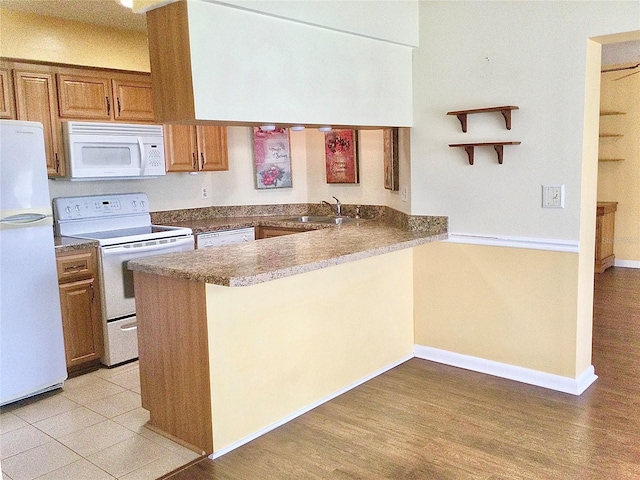 kitchen with sink, light hardwood / wood-style floors, kitchen peninsula, and white appliances