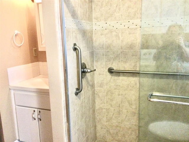 bathroom featuring a shower with door and vanity