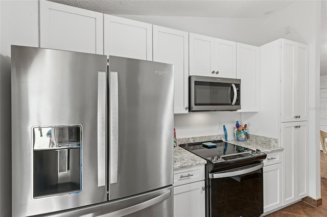 kitchen with appliances with stainless steel finishes, lofted ceiling, white cabinetry, and light stone countertops