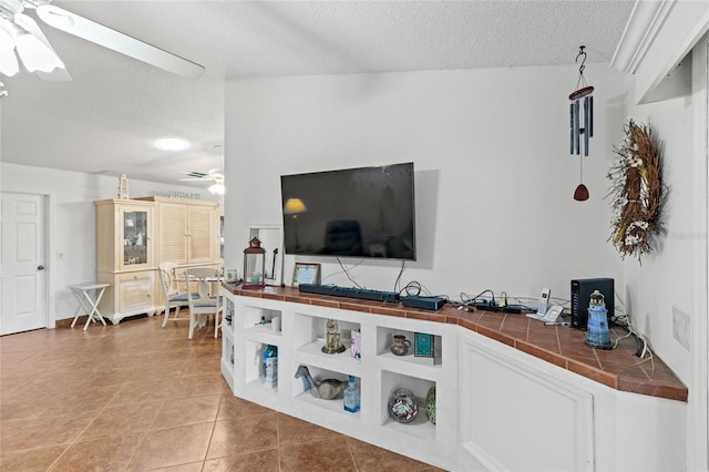 tiled living room with ceiling fan, a textured ceiling, and lofted ceiling