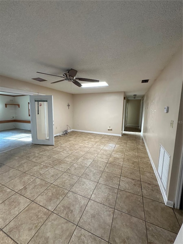 interior space featuring a textured ceiling, light tile patterned floors, and ceiling fan