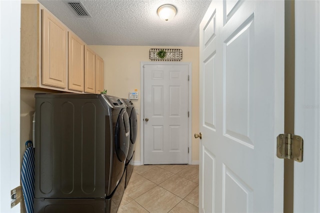 clothes washing area with separate washer and dryer, a textured ceiling, cabinets, and light tile patterned flooring