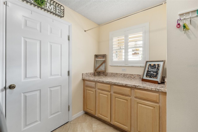 interior space with tile patterned floors, vanity, and a textured ceiling