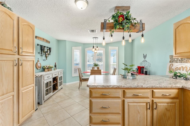 kitchen with pendant lighting, a textured ceiling, light brown cabinetry, and light tile patterned floors