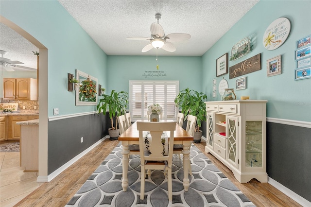 dining room with a textured ceiling, light hardwood / wood-style flooring, and ceiling fan