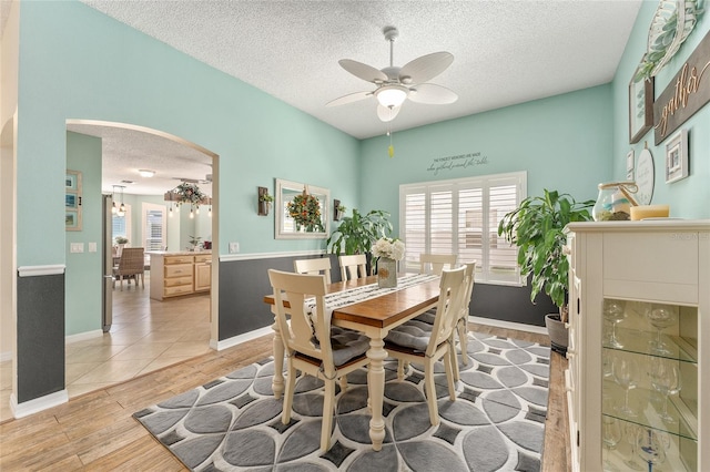 dining room with light wood-type flooring, ceiling fan, and a textured ceiling