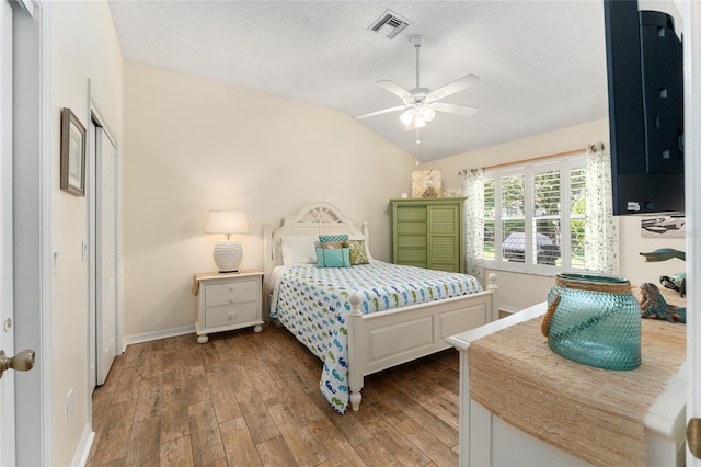 bedroom featuring ceiling fan, dark hardwood / wood-style floors, a textured ceiling, and vaulted ceiling