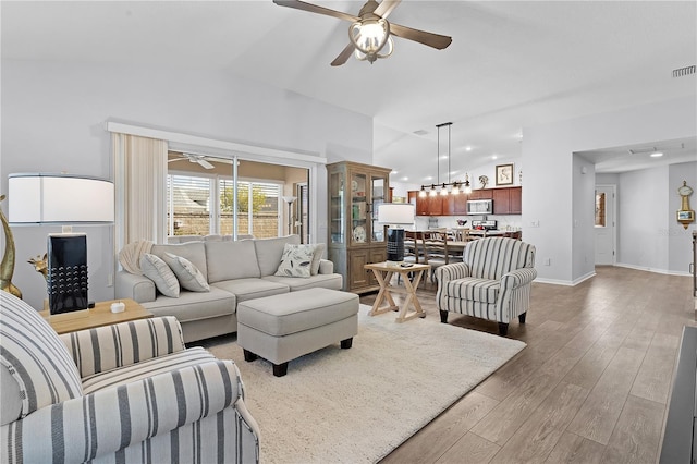 living room featuring ceiling fan, hardwood / wood-style flooring, and vaulted ceiling