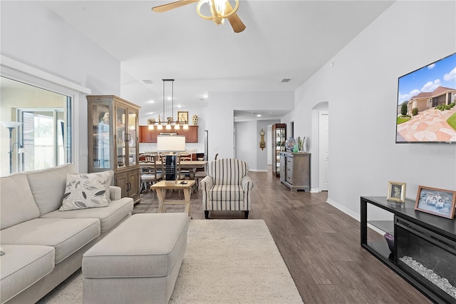 living room featuring ceiling fan with notable chandelier and dark hardwood / wood-style floors