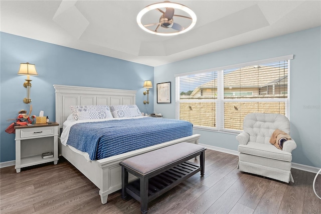 bedroom featuring a tray ceiling, ceiling fan, and dark wood-type flooring