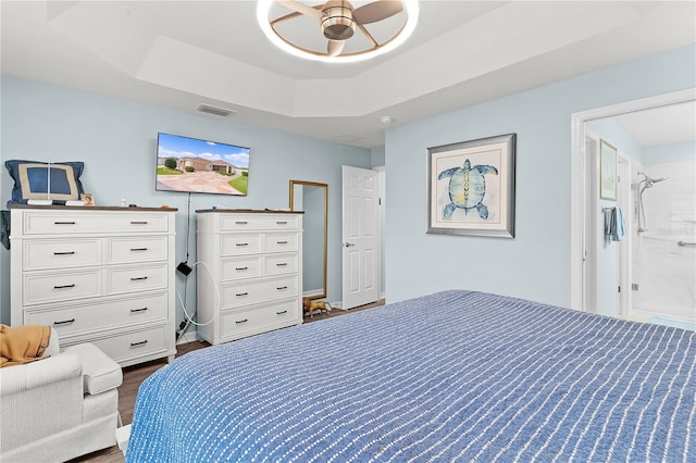 bedroom with a raised ceiling, ensuite bath, ceiling fan, and dark hardwood / wood-style flooring