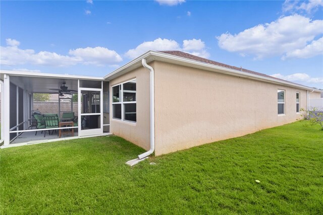 rear view of house with a yard, ceiling fan, and a sunroom