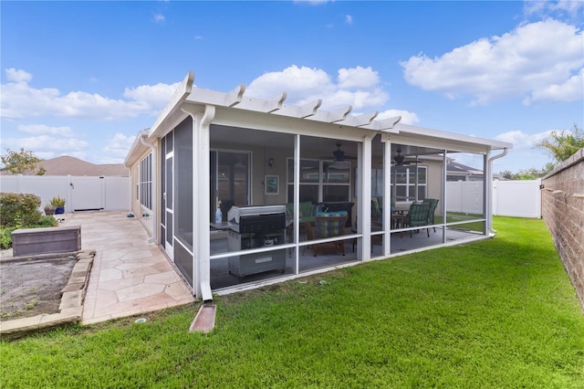 rear view of house featuring a sunroom, a lawn, and a patio area