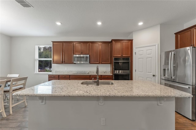 kitchen featuring an island with sink, a breakfast bar area, and appliances with stainless steel finishes