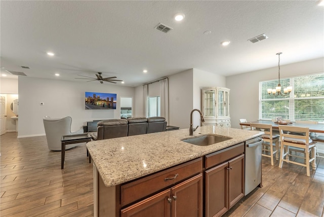 kitchen featuring ceiling fan with notable chandelier, dark hardwood / wood-style flooring, pendant lighting, a kitchen island with sink, and sink