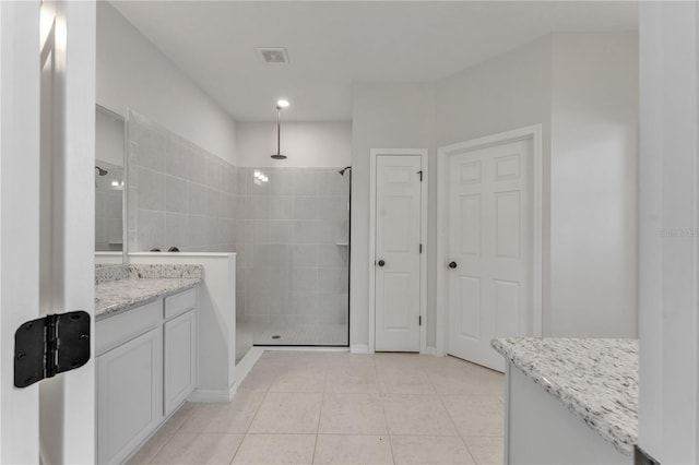 bathroom with tile patterned floors, tiled shower, and vanity