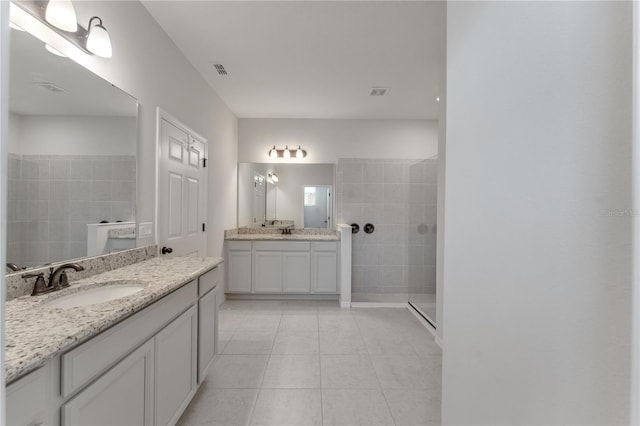 bathroom featuring vanity, tile patterned floors, and a tile shower