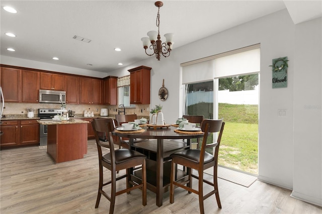 dining space with plenty of natural light, an inviting chandelier, and light wood-type flooring