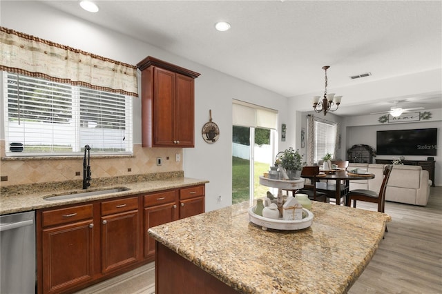 kitchen featuring dishwasher, a center island, sink, decorative backsplash, and light wood-type flooring