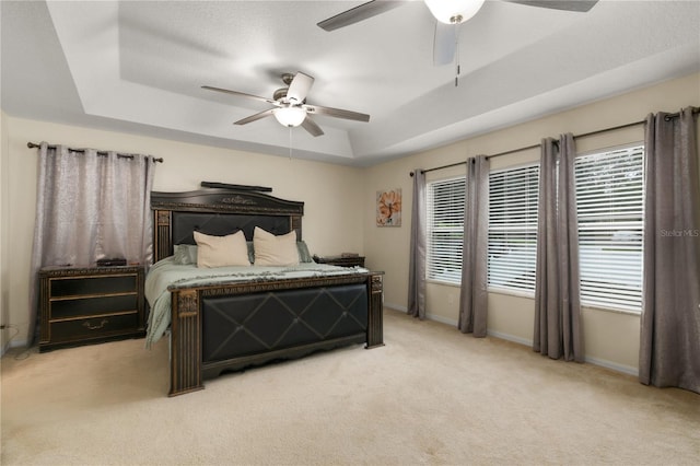 bedroom with multiple windows, ceiling fan, and a raised ceiling