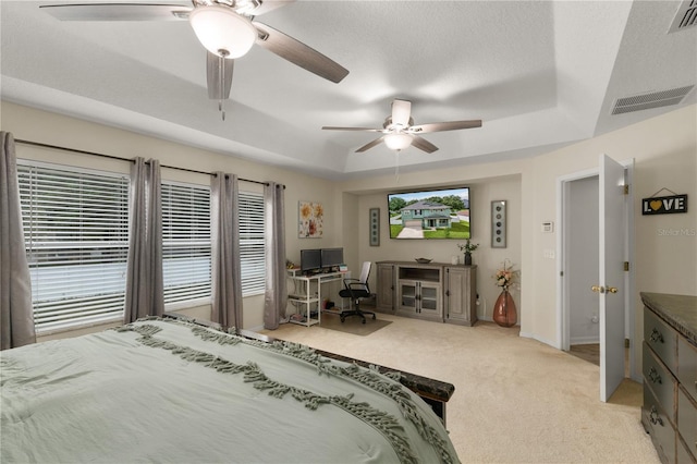 bedroom with a raised ceiling, ceiling fan, light carpet, and multiple windows