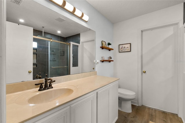 bathroom featuring a shower with door, vanity, a textured ceiling, toilet, and hardwood / wood-style flooring