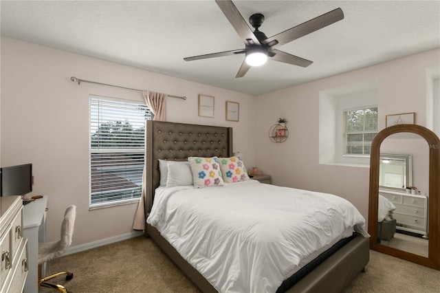 bedroom with a textured ceiling, ceiling fan, light carpet, and multiple windows