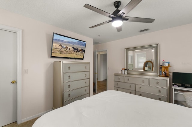 carpeted bedroom with ceiling fan and a textured ceiling