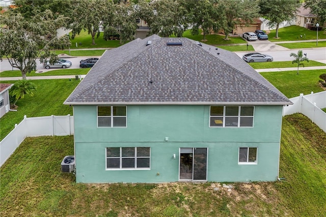 rear view of house featuring central AC and a yard