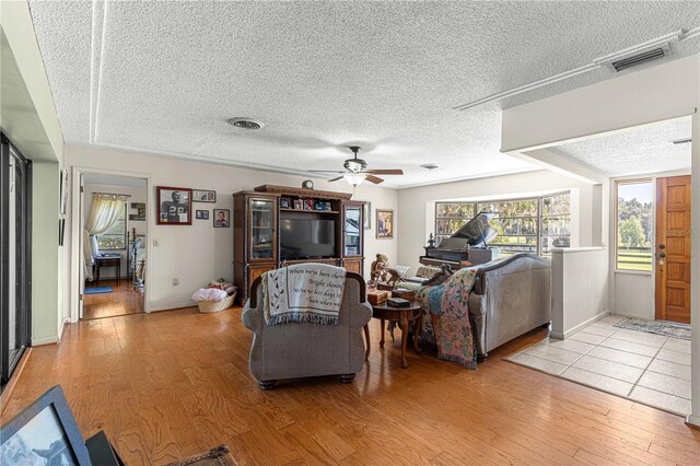 living room with a textured ceiling, light hardwood / wood-style floors, and ceiling fan