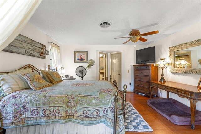 bedroom with ceiling fan, a textured ceiling, and hardwood / wood-style floors