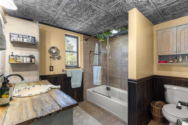 full bathroom with vanity, wooden walls, tiled shower / bath combo, and toilet