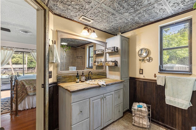 bathroom featuring a wealth of natural light, wooden walls, hardwood / wood-style floors, and vanity