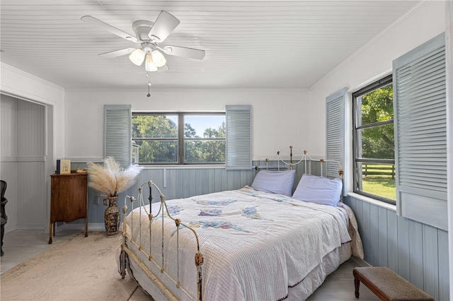 bedroom with ceiling fan, crown molding, and wood walls