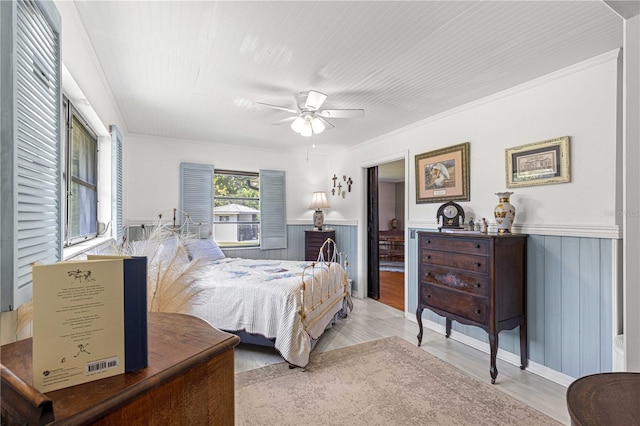 bedroom with light hardwood / wood-style floors, ceiling fan, wood walls, and crown molding