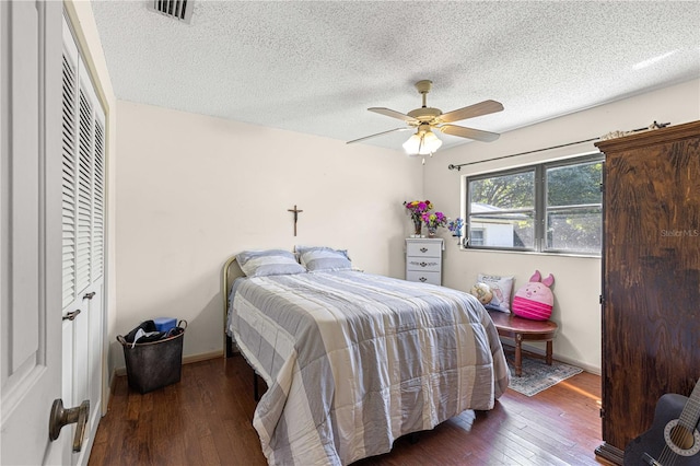 bedroom with ceiling fan, a textured ceiling, and dark hardwood / wood-style floors